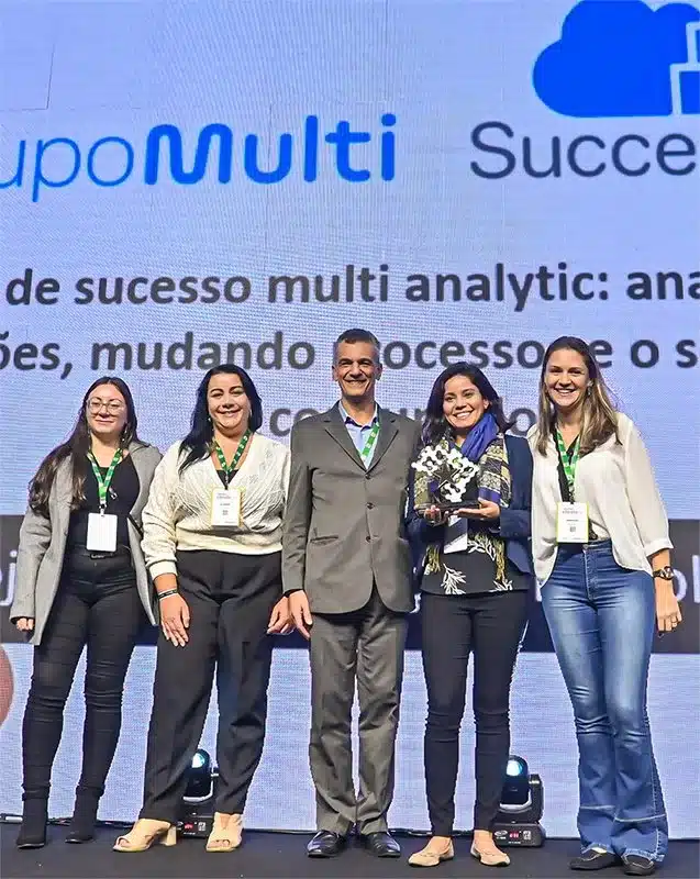 Group of five people on stage, smiling, with one holding an award.