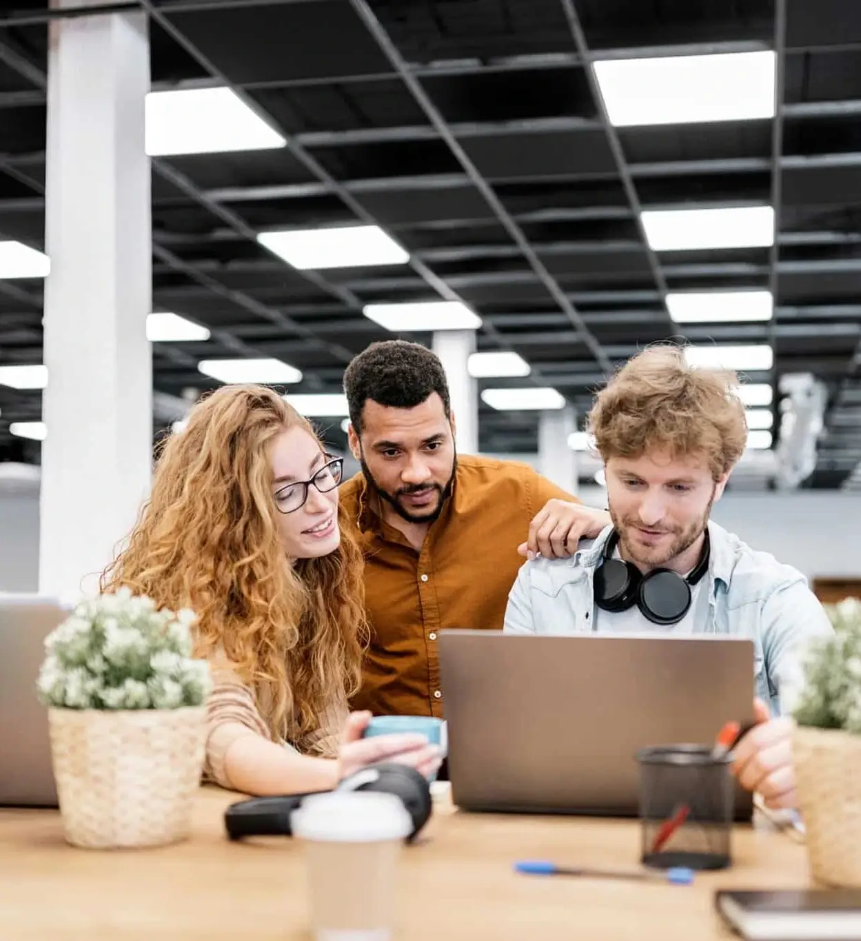 Stock photo of three office workers using a computer. They are looking to the screen and seem concentrated. Co-working concept.